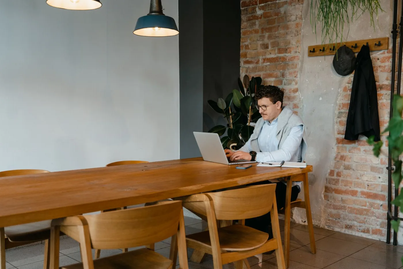 Iemand werkt alleen aan een laptop aan een lange houten tafel